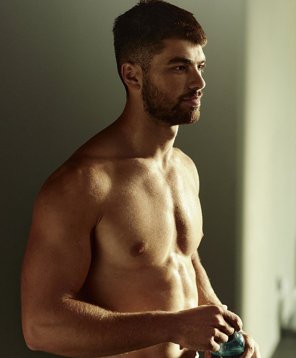Man holding water bottle in soft lighting.