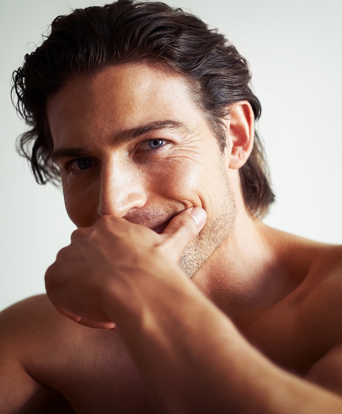 Smiling man with hand on face, casual pose.