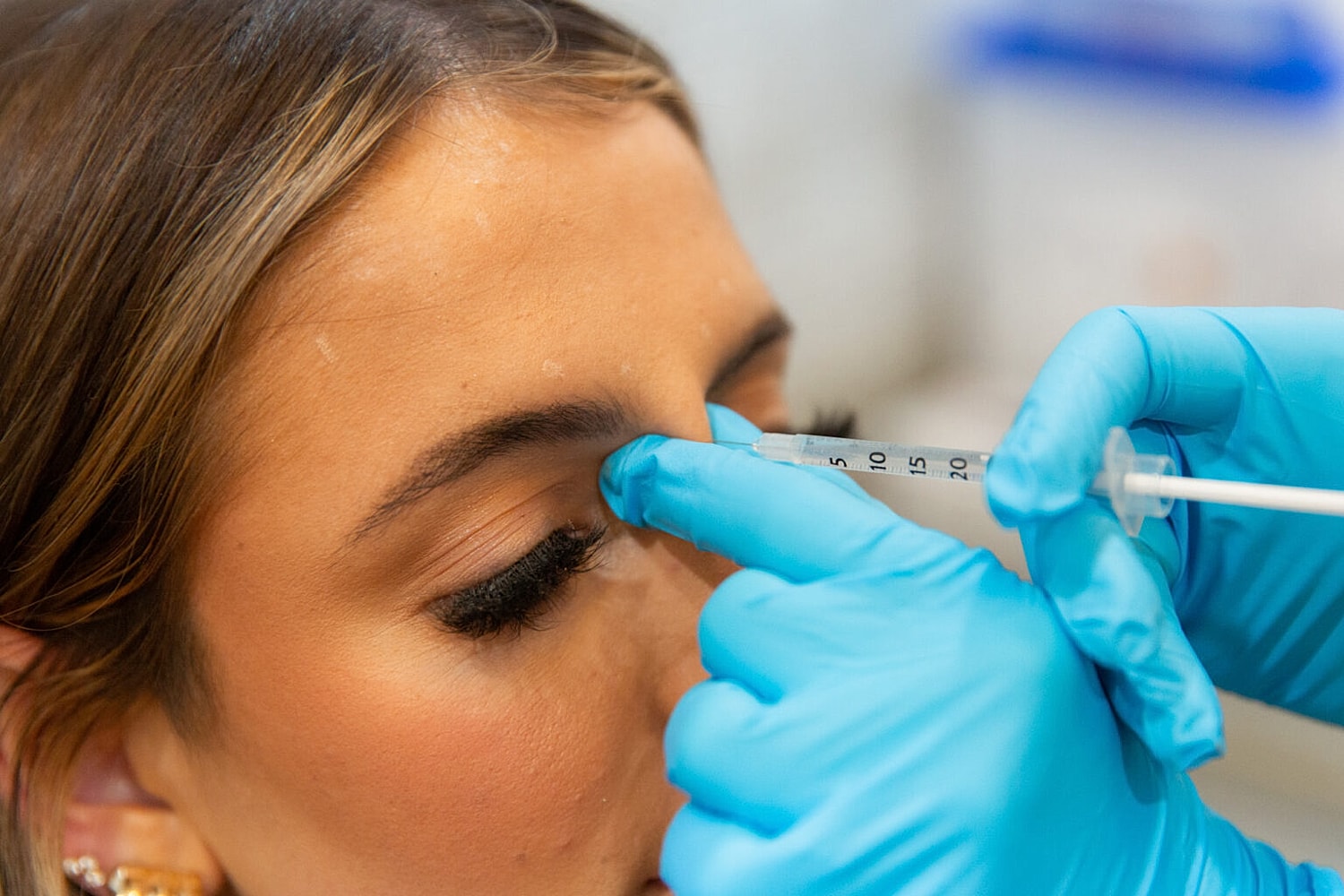 Administering cosmetic injection near eye.
