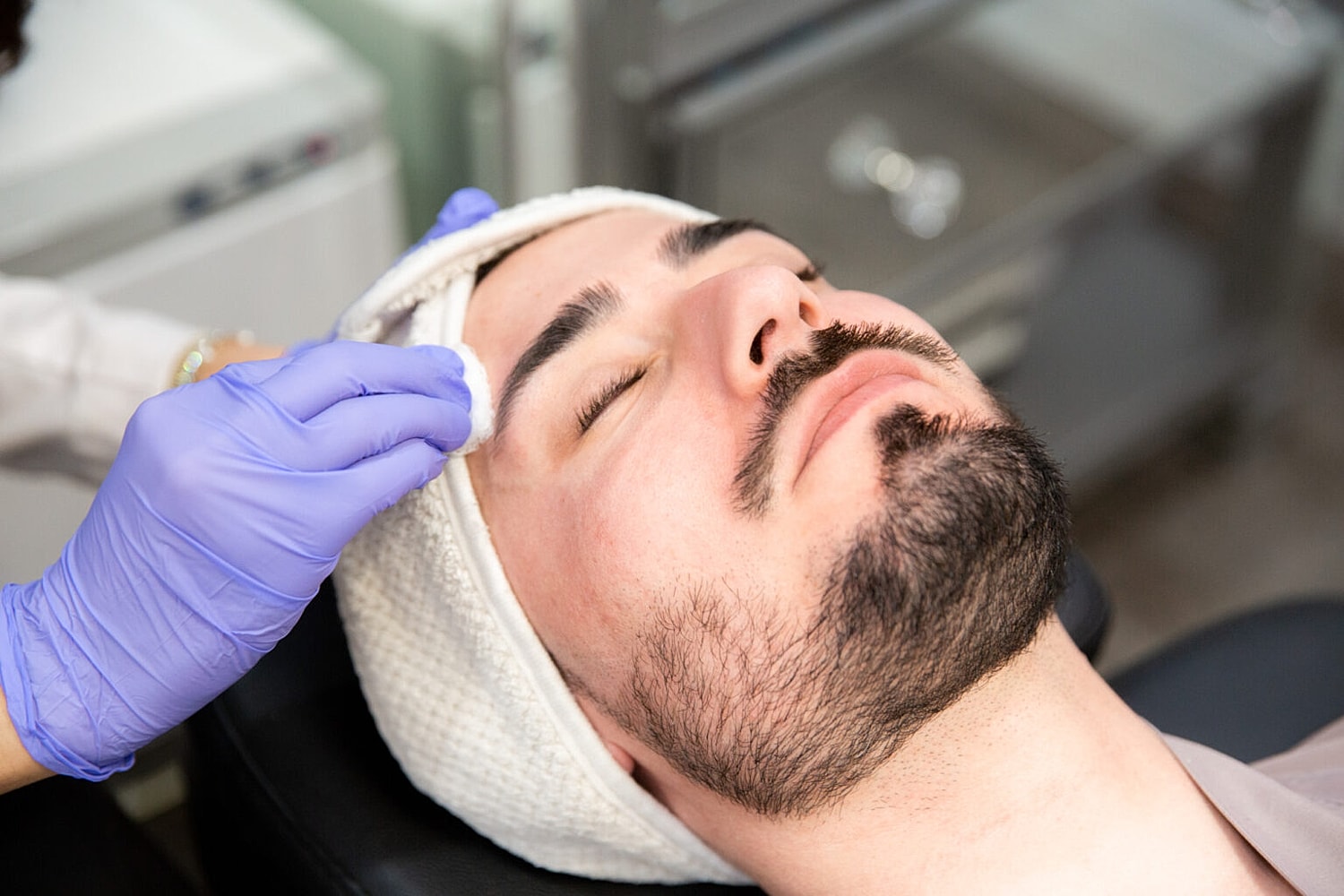Man receiving facial treatment in a clinic.