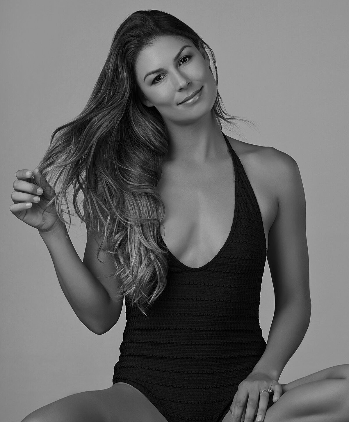 Woman in black swimsuit, smiling and relaxed.