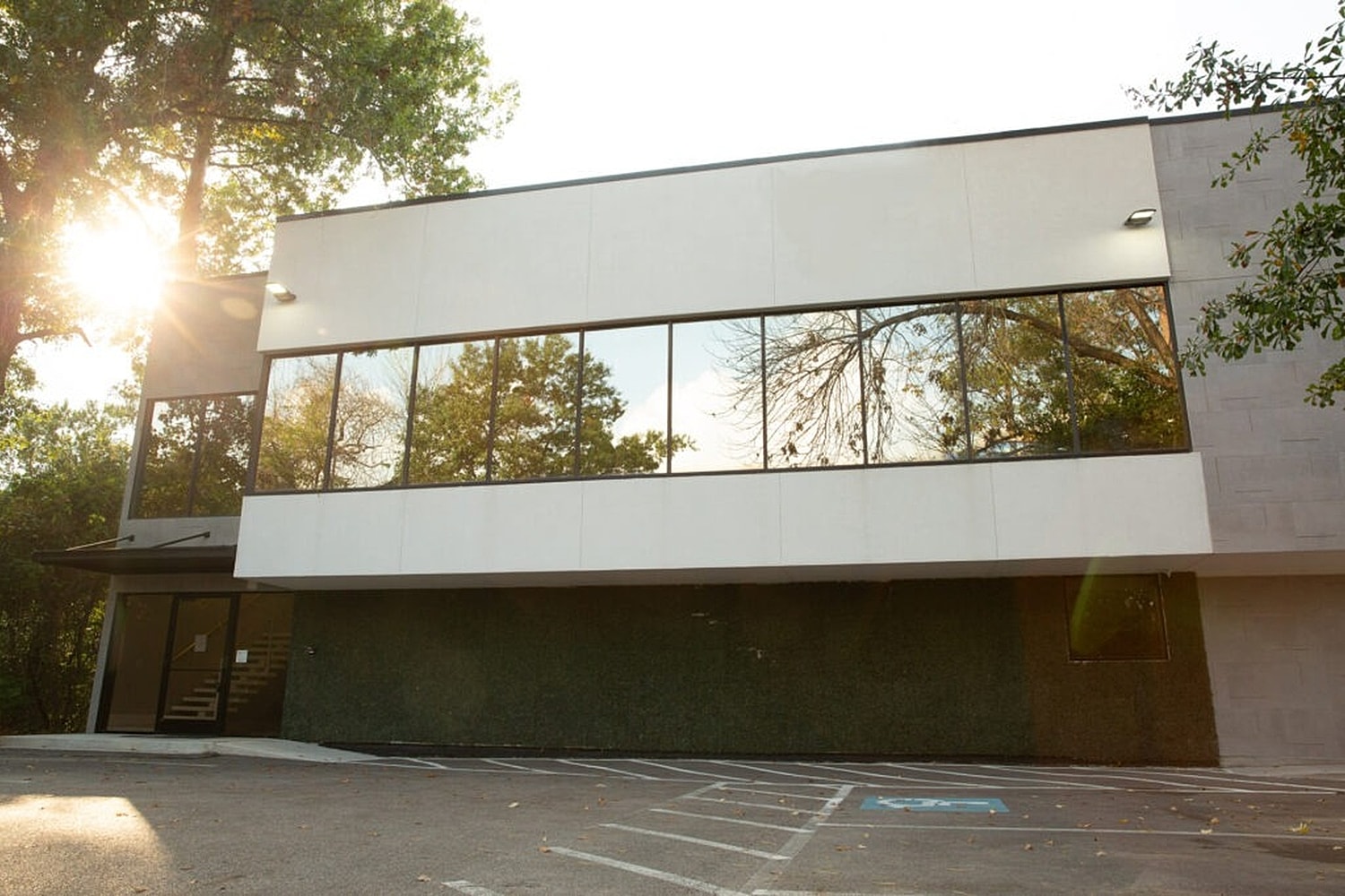 Modern building with large windows and greenery.