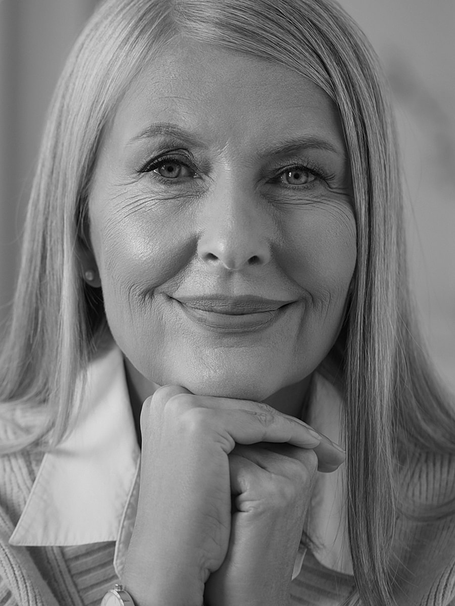 Smiling older woman with silver hair, thoughtful expression.