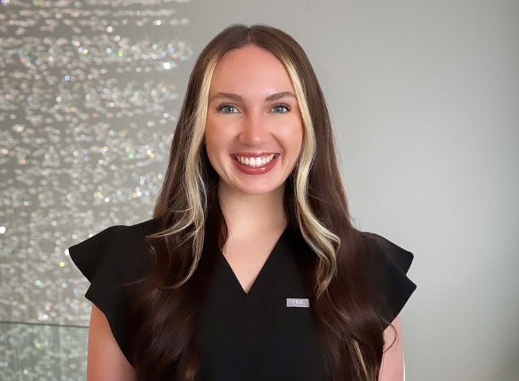 Smiling woman in black outfit with long hair.