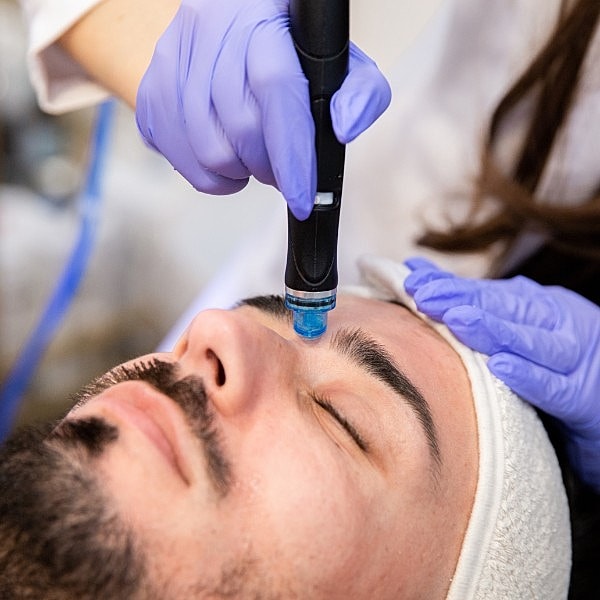 Man receiving facial treatment with a handheld device.