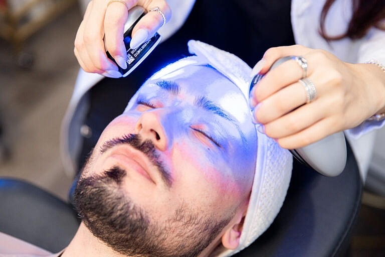 Facial treatment with blue light therapy in progress.