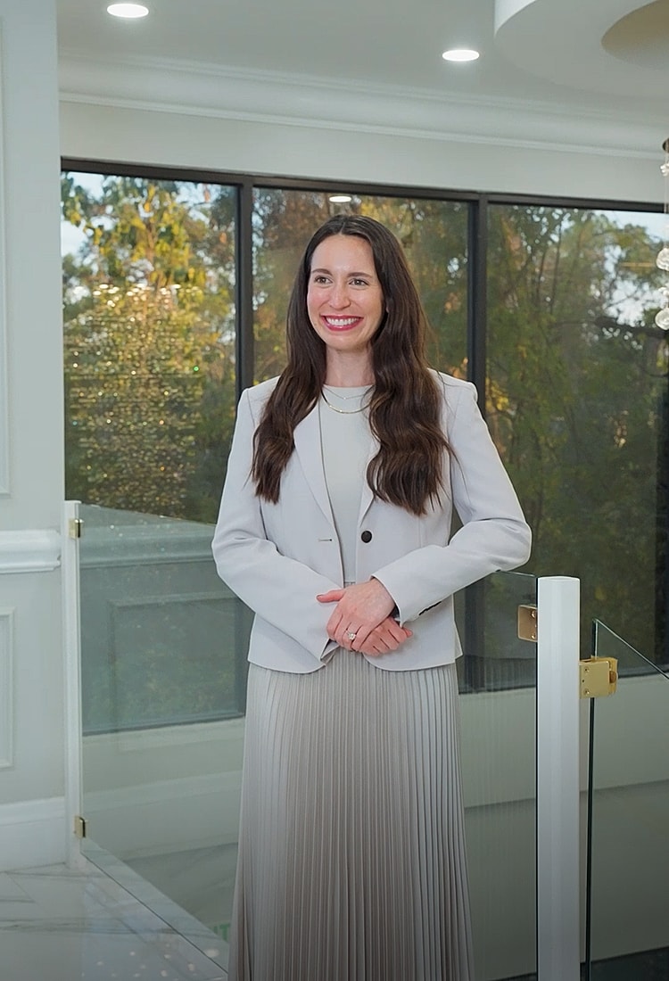 Woman in professional attire standing indoors.